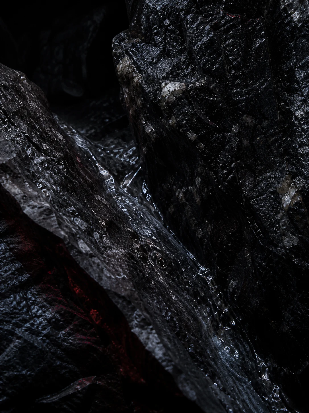 Art-directed study of clear water moving through dark mineral rock